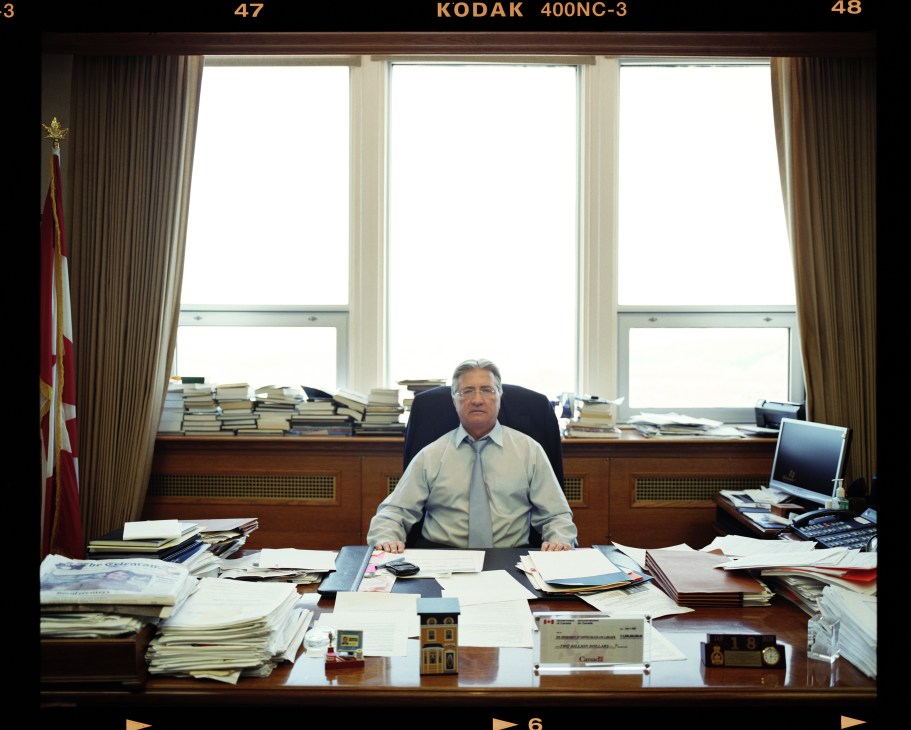 Premier Danny Williams sits at his desk in his eighth-floor office, surrounded by stacks of papers and documents.