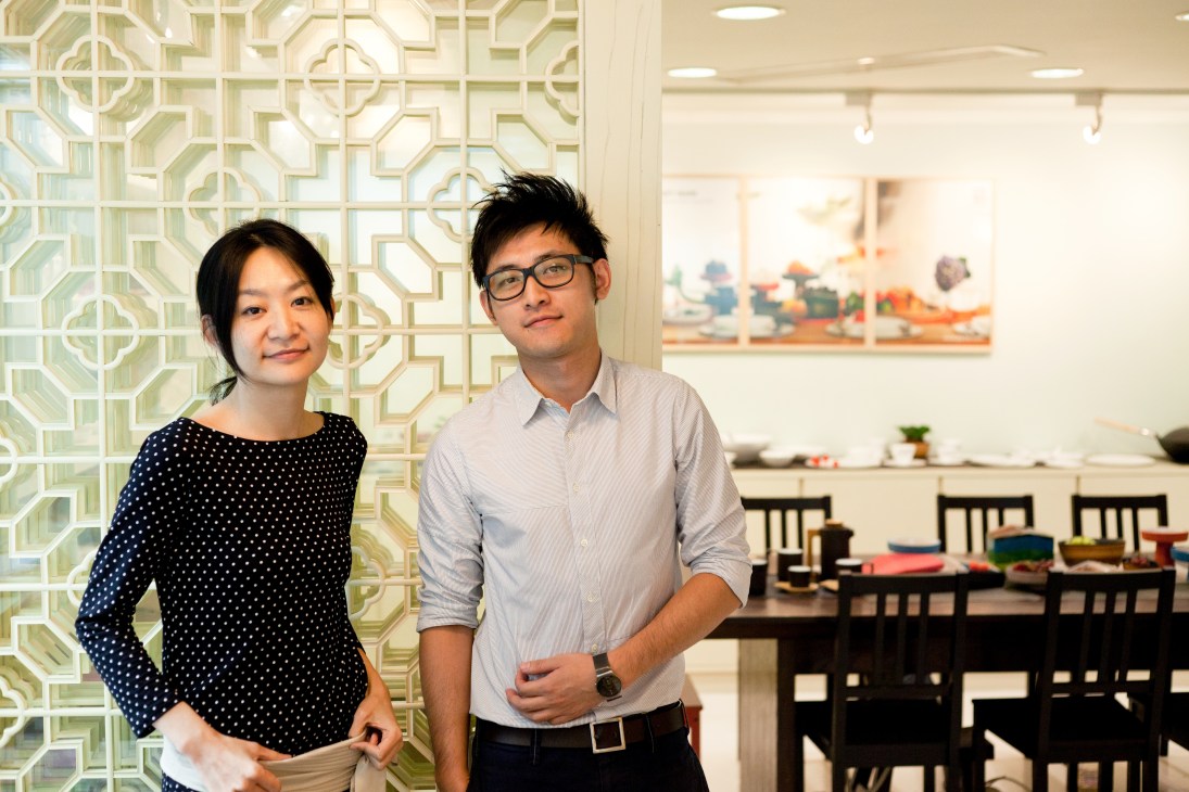 Two professionals stand in a modern office with geometric patterned room divider, Jia Inc brand director Claire Chen and brand executive Brian Khoo.
