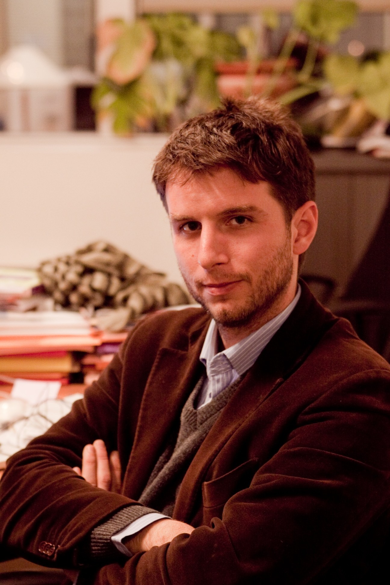 Senior correspondent Alfred de Montesquiou sits at a desk in an office setting, wearing a brown blazer and light shirt.