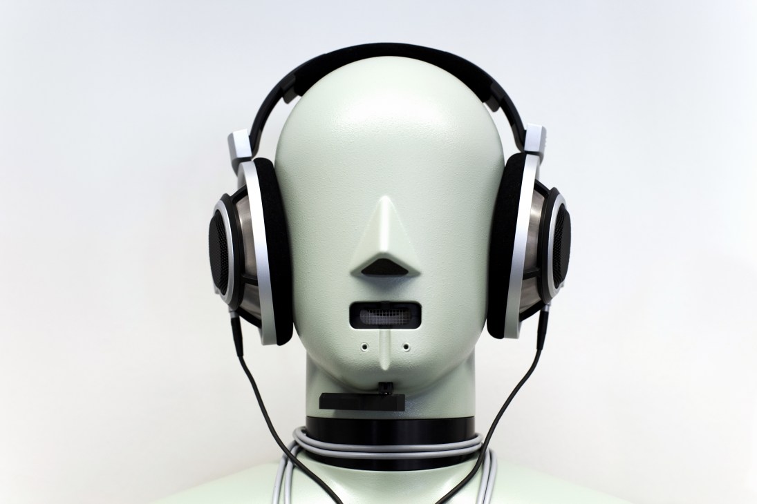 Mannequin head wearing black and white over-ear headphones against a light background.