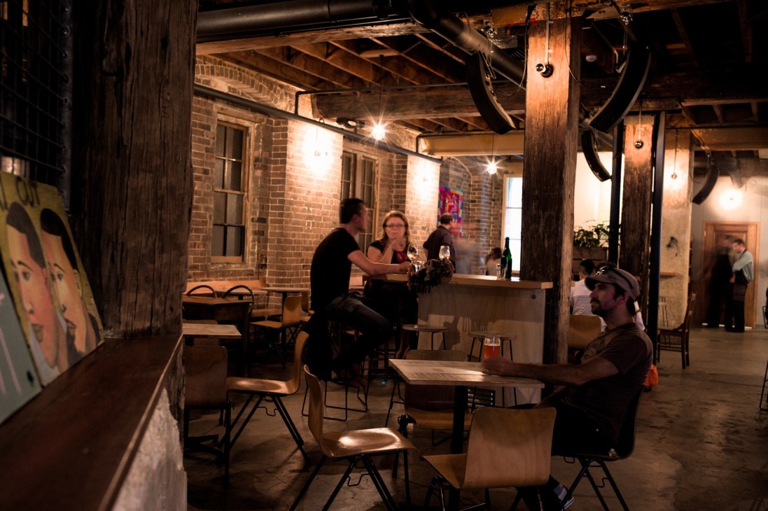 Interior of Freda's bar in Chippendale with exposed brick, wooden beams, bar counter, and patrons seated at tables