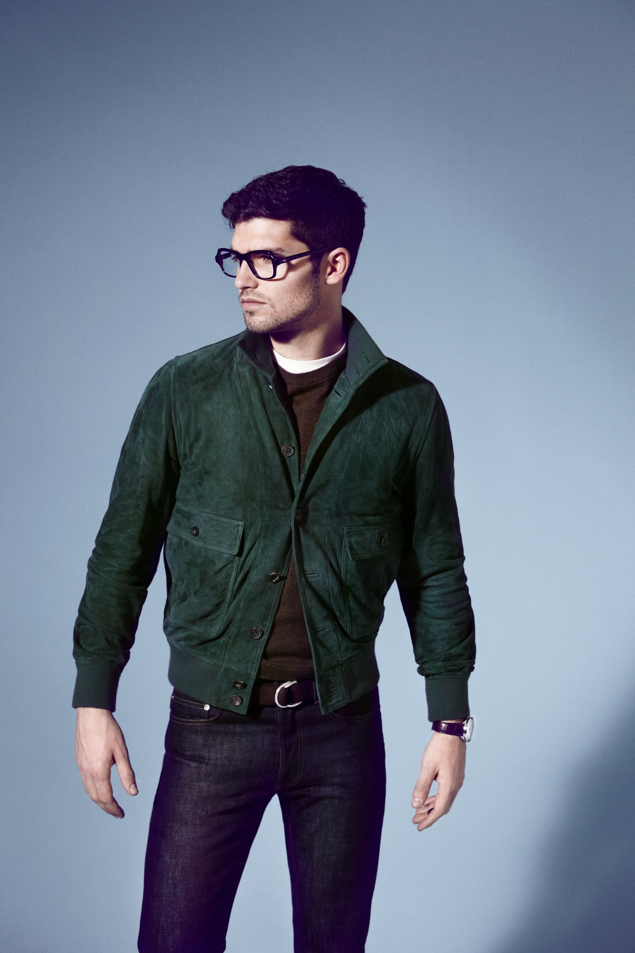 Male model wearing green Valstarino jacket, brown knit by Yaeca, dark Dior Homme jeans, and Claire Goldsmith glasses.