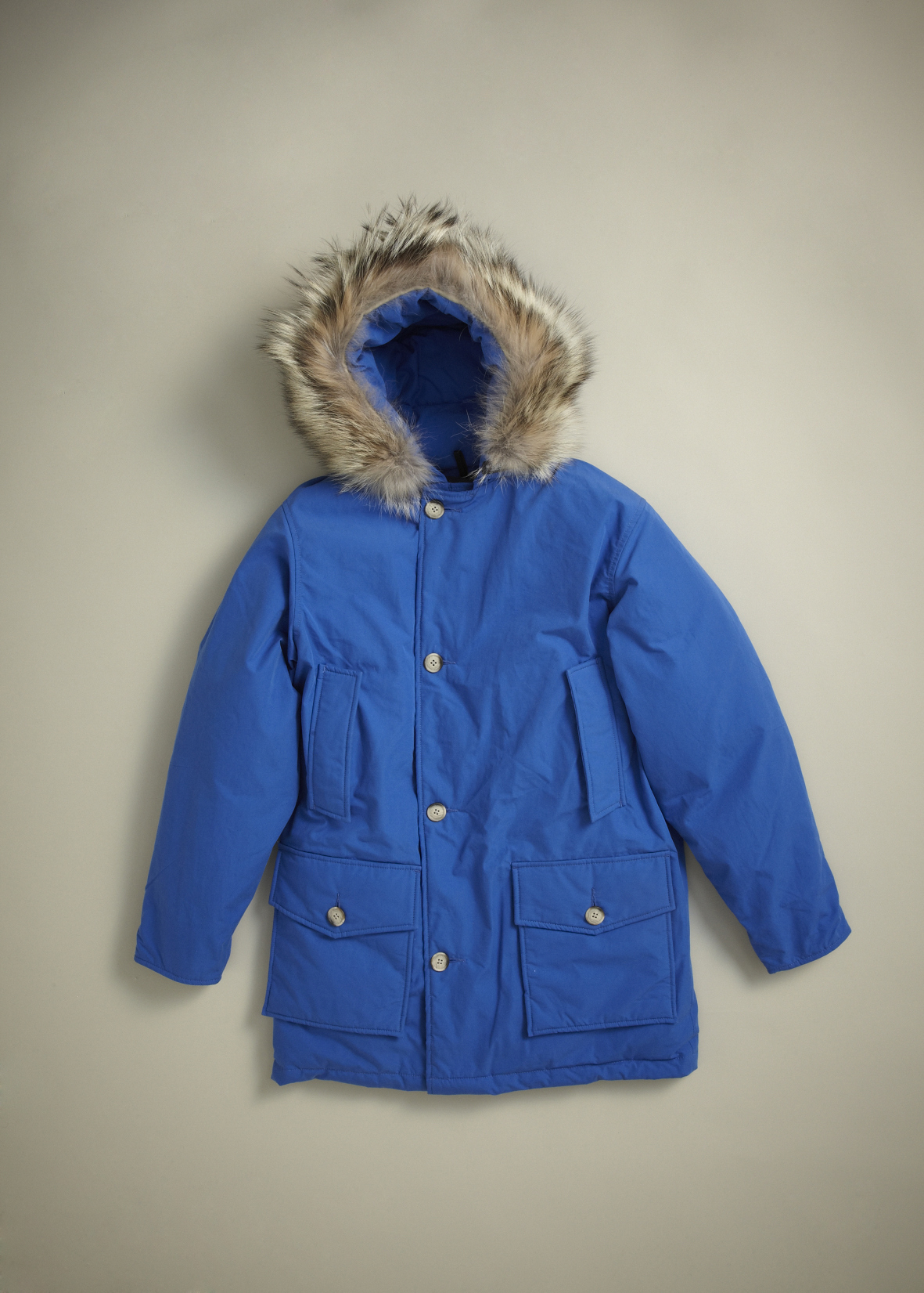 Royal blue Woolrich Arctic Parka with fur-lined hood and chest pockets displayed on neutral background.