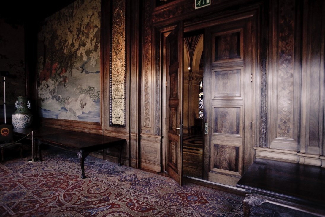 Ornate interior hallway with carved wooden doors, decorative wall panels, and patterned carpet at the Peace Palace.