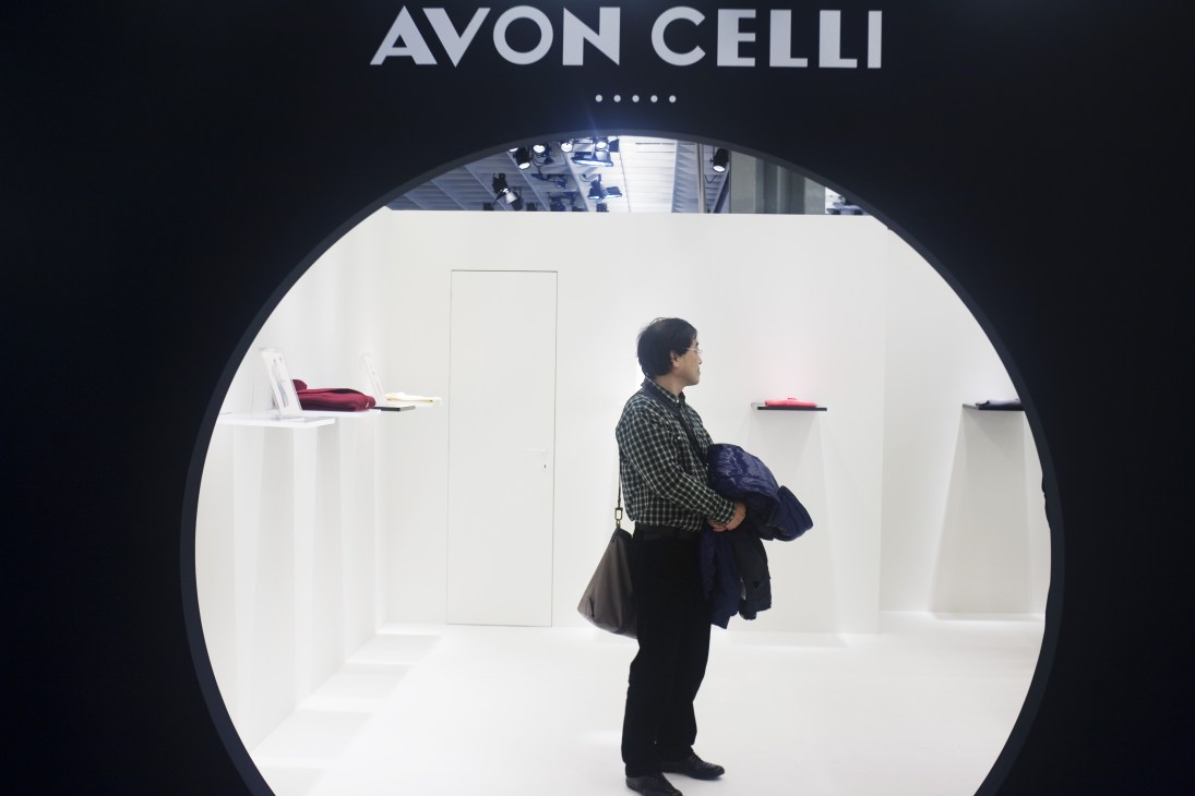 Visitor browsing the Avon Celli stand displaying knitwear at Pitti Uomo menswear show.