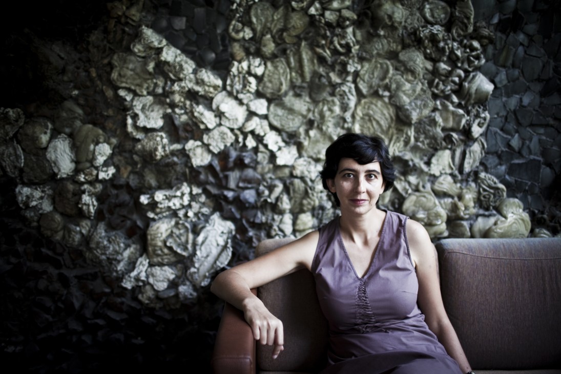 Joanna Mytkowska, director of the Museum of Modern Art, sits on a grey sofa against a textured stone wall.