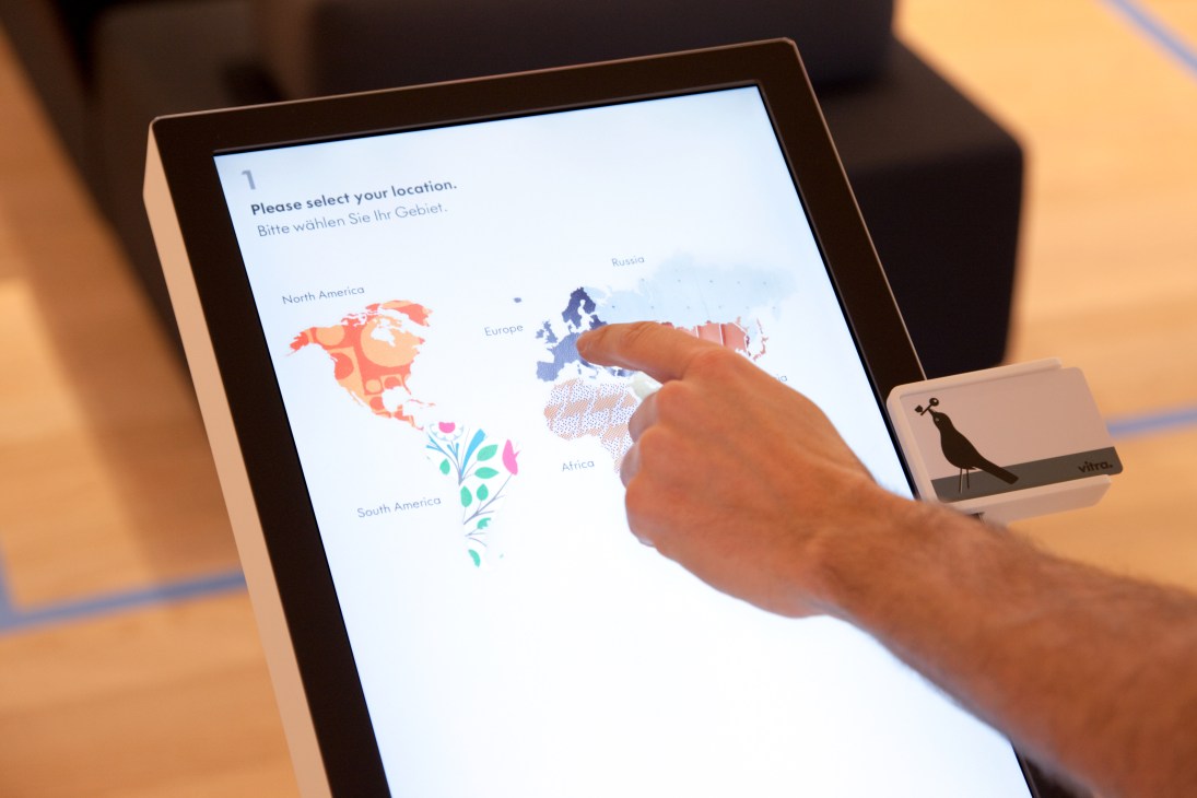 Hand selecting Europe on an interactive touchscreen map display at Vitrahaus.