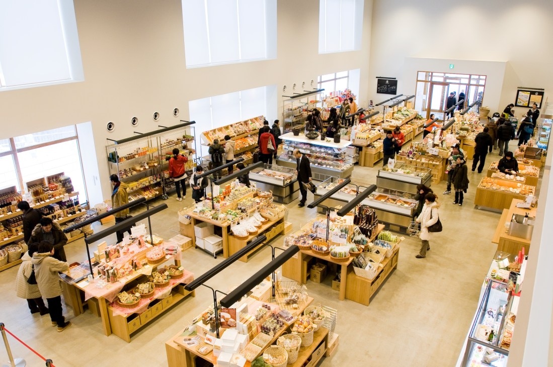 Overhead view of Food Marché with shoppers browsing displays of local Aomori products on wooden tables and shelves.