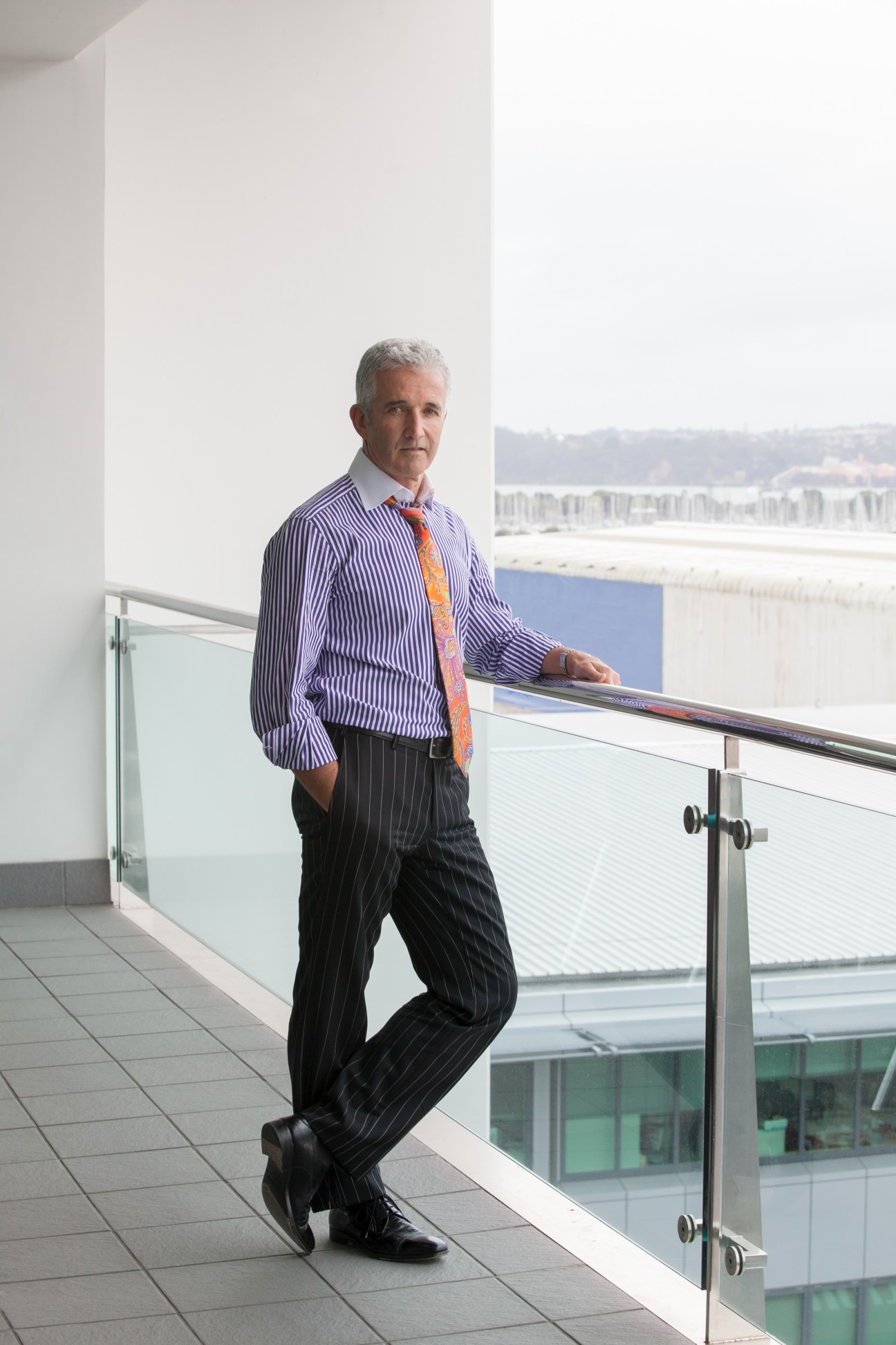 Rob Fyfe, Air New Zealand CEO, stands on a modern balcony overlooking a waterfront cityscape.
