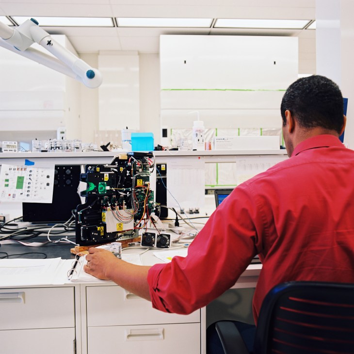 Person in red shirt working on iCubate device in HudsonAlpha laboratory.