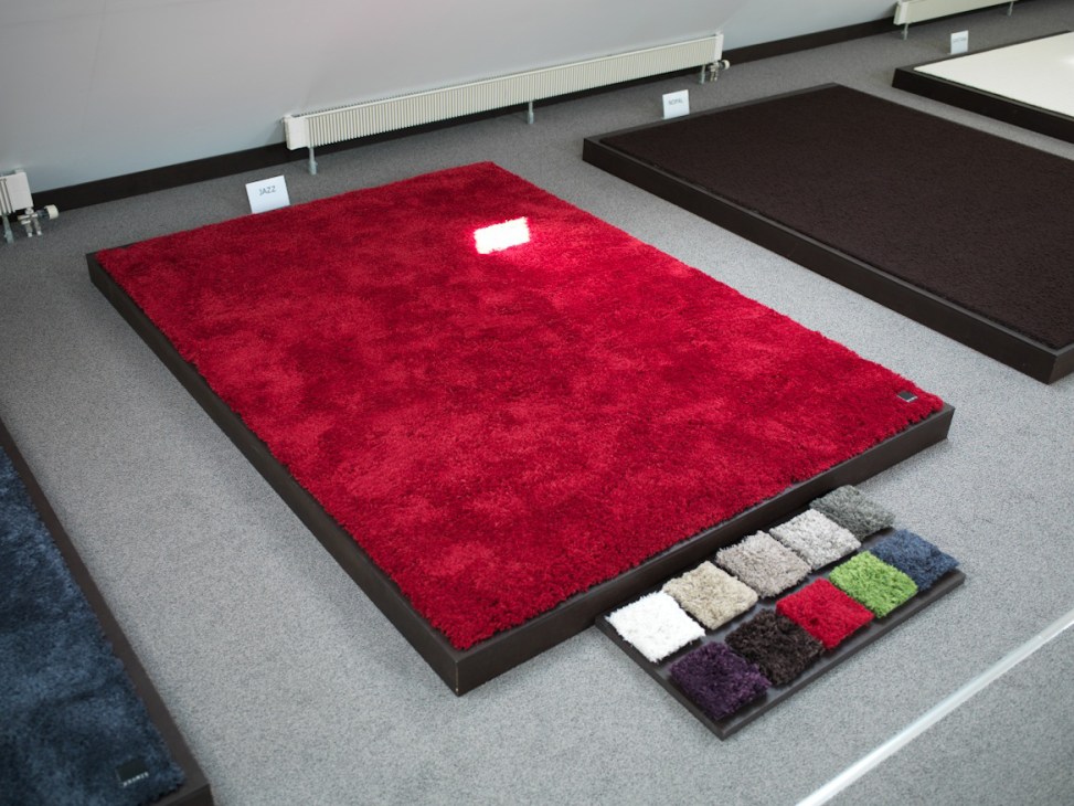 Kramis carpet samples displayed in showroom including red, cream, green and purple swatches