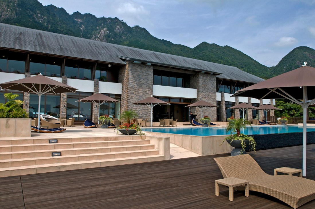 Sankara Hotel's decked infinity pool with mountain backdrop and lounge seating.