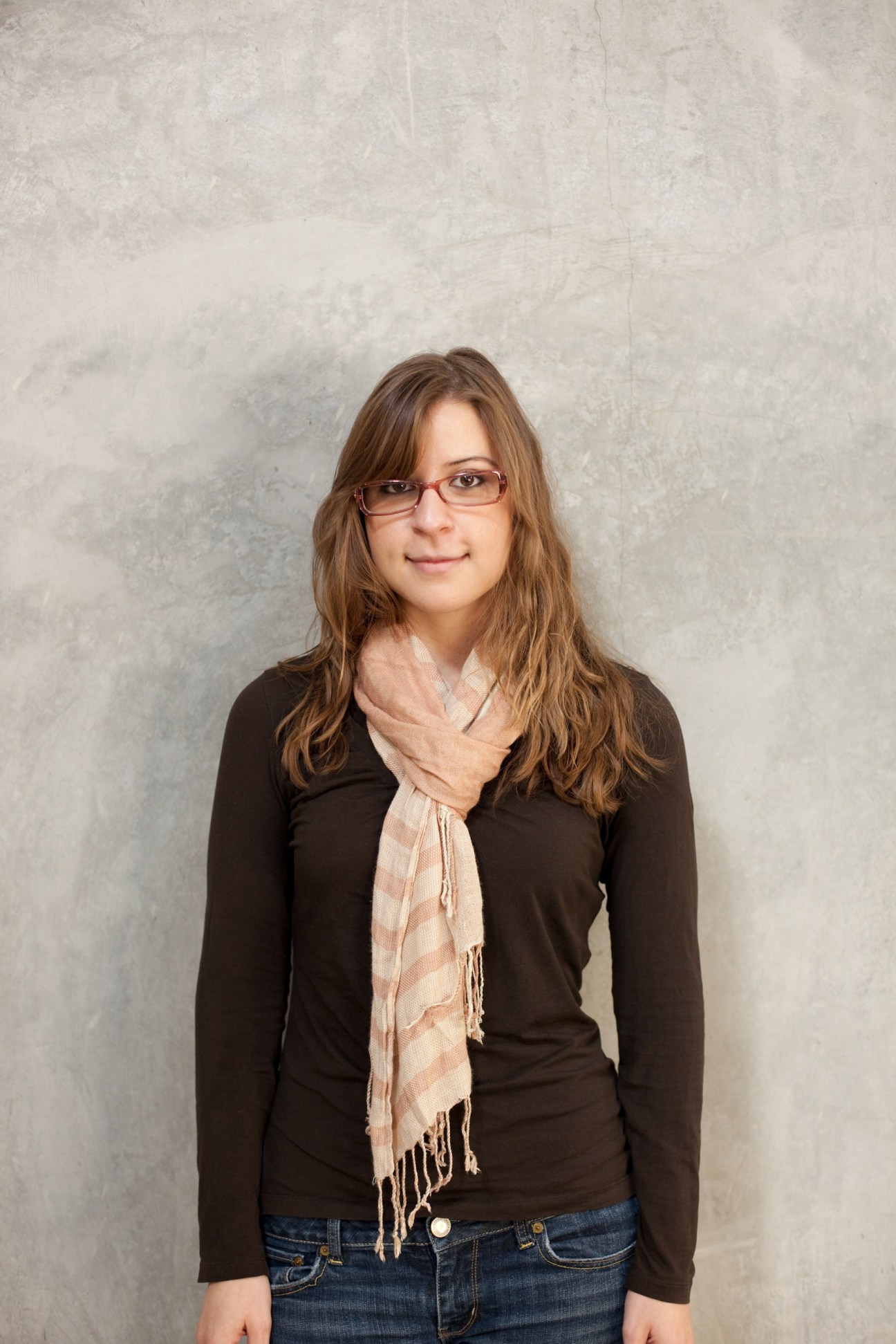 Portrait of d.school student Reyna Kontos wearing glasses and a black long-sleeve top with a pink scarf.