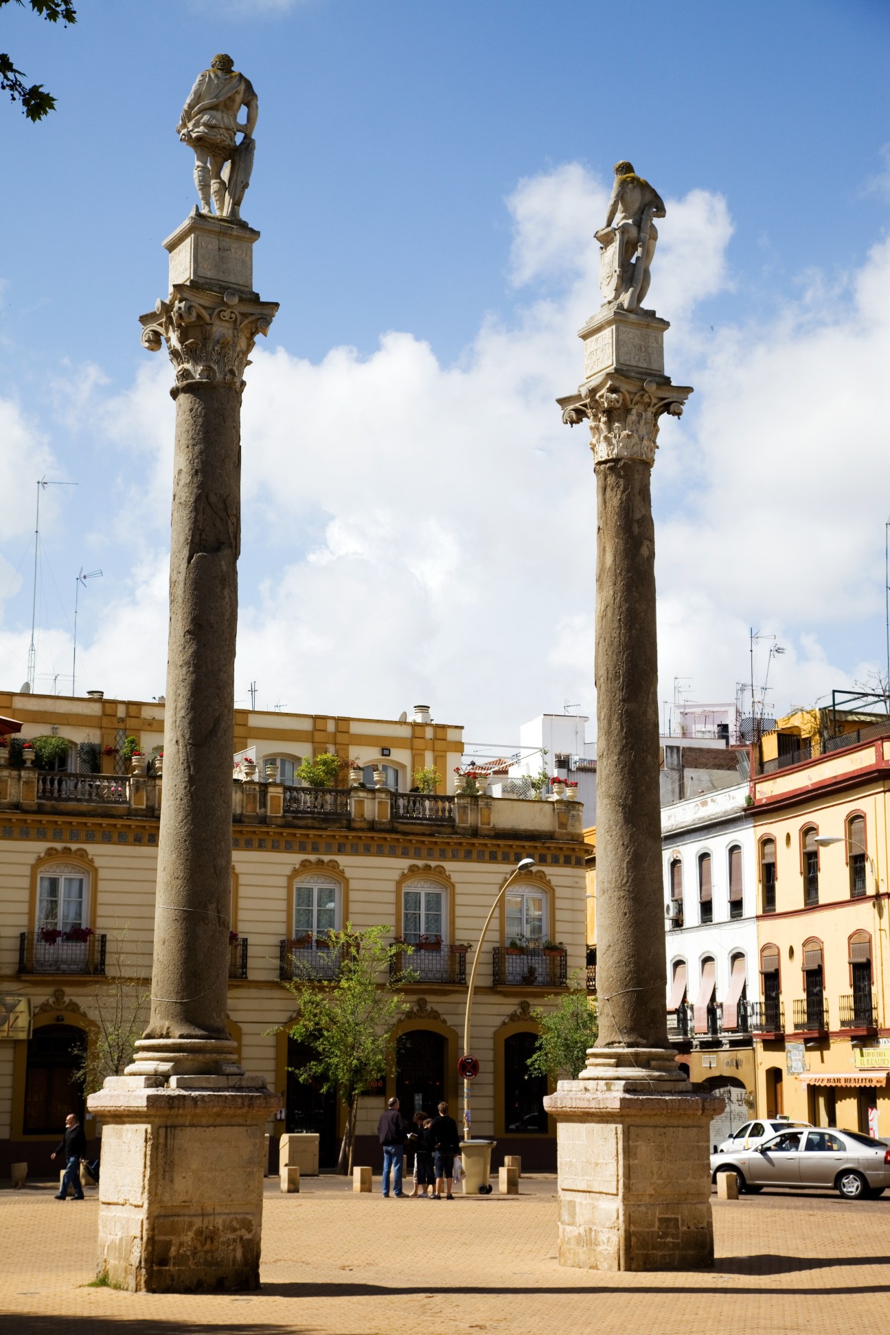 Two tall ornate Roman columns topped with statues in Alameda de Hércules plaza, Seville.