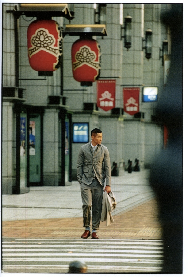 Model Yusuke walks through a Fukuoka street with red lanterns overhead, wearing Woolrich Woolen Mills jacket and trousers with a Needles shirt.