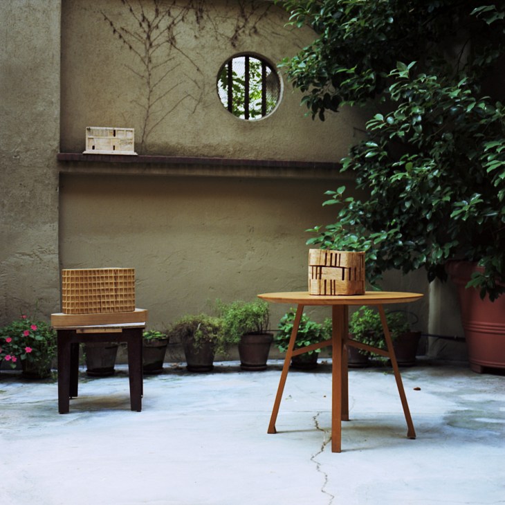 Wooden architectural models displayed on furniture in De Lucchi's Milan studio garden courtyard.