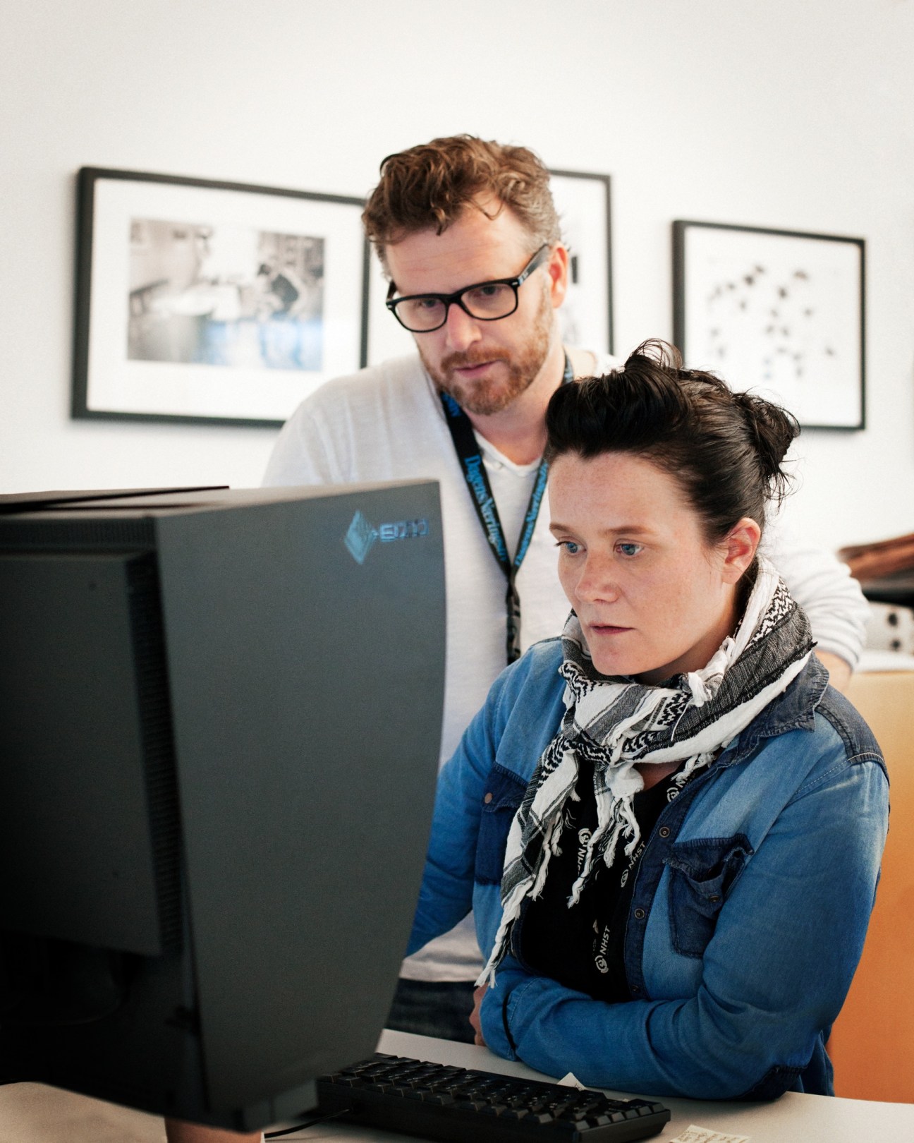 Two photo editors working together at a computer in Dagens Næringsliv newsroom in Oslo.