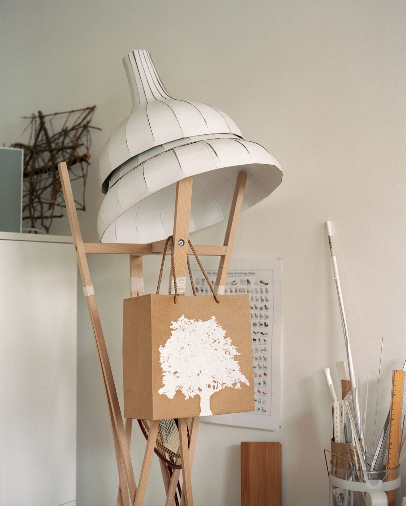 Tra coatstand for Zilio featuring a white pleated shade and wooden frame in a design studio.