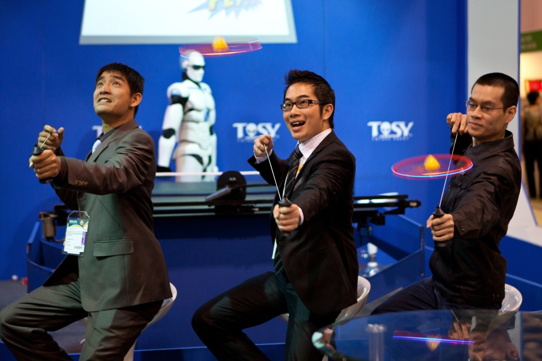 Three men in business suits demonstrating flying toys at the Hong Kong Toys & Games Fair.