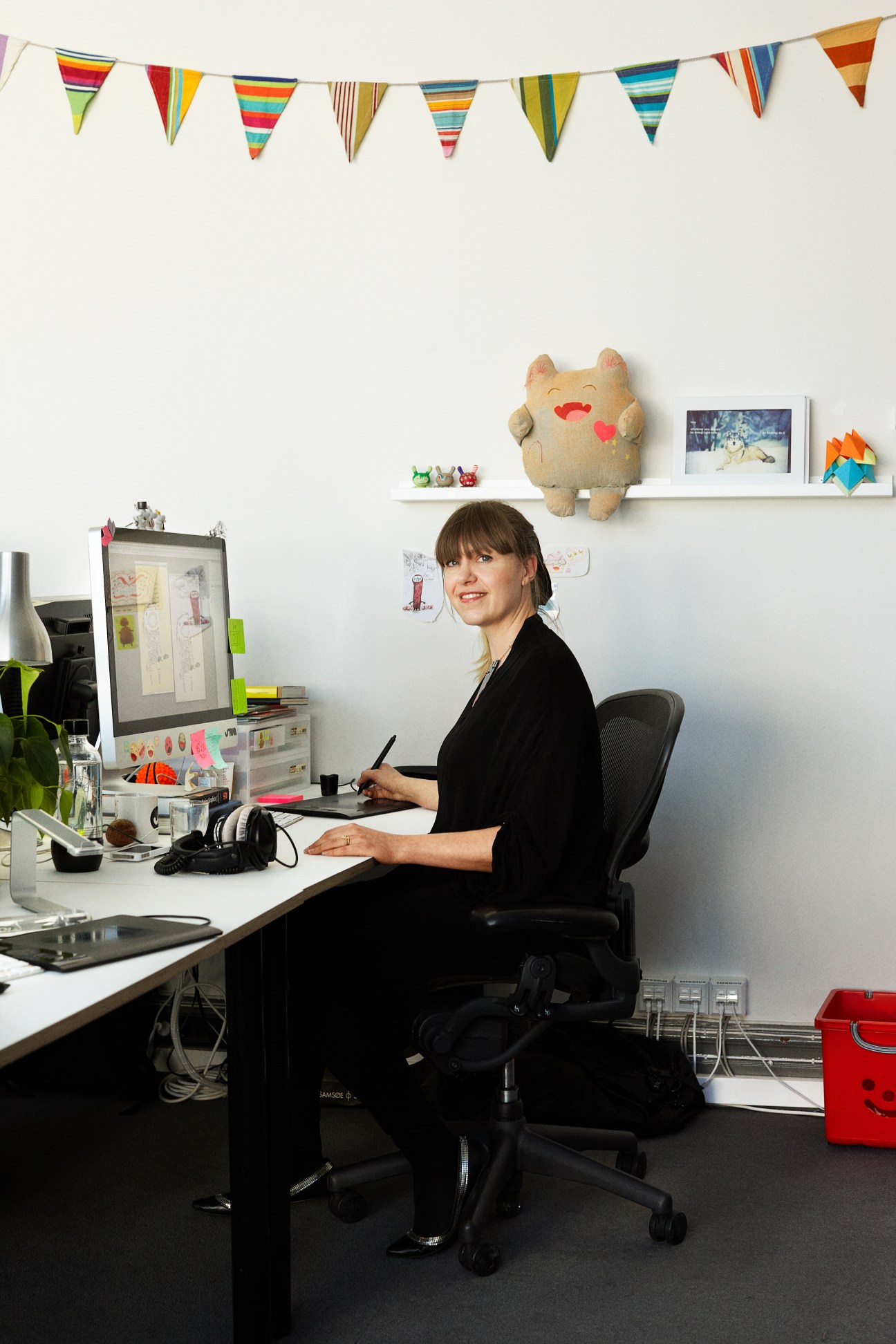 Kristina Gordon, visual designer at ustwo, sits at her desk in a creative workspace with colorful bunting and design materials.