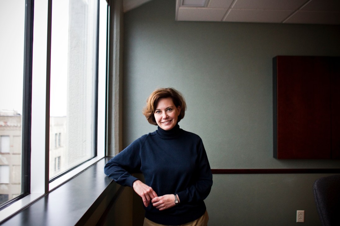 Woman in navy turtleneck standing by window in modern office space