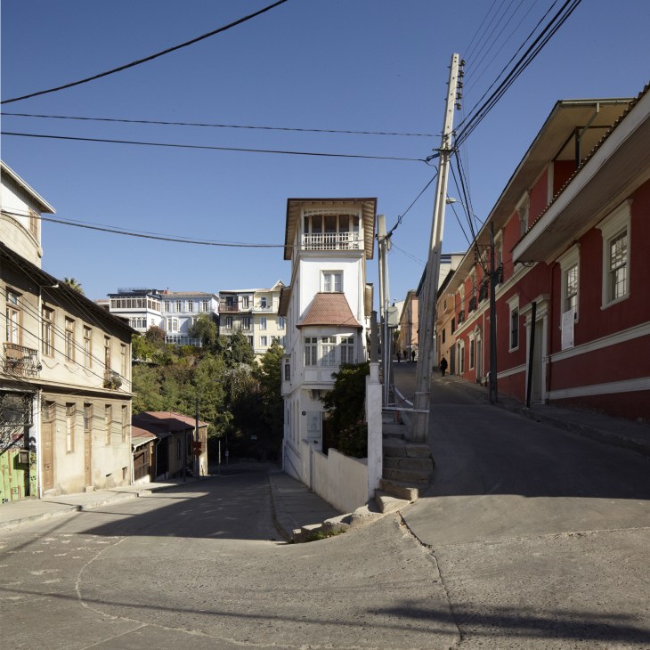 Colorful Victorian buildings line a steep street in Valparaiso's Cerro Alegre neighborhood with clear blue sky above.