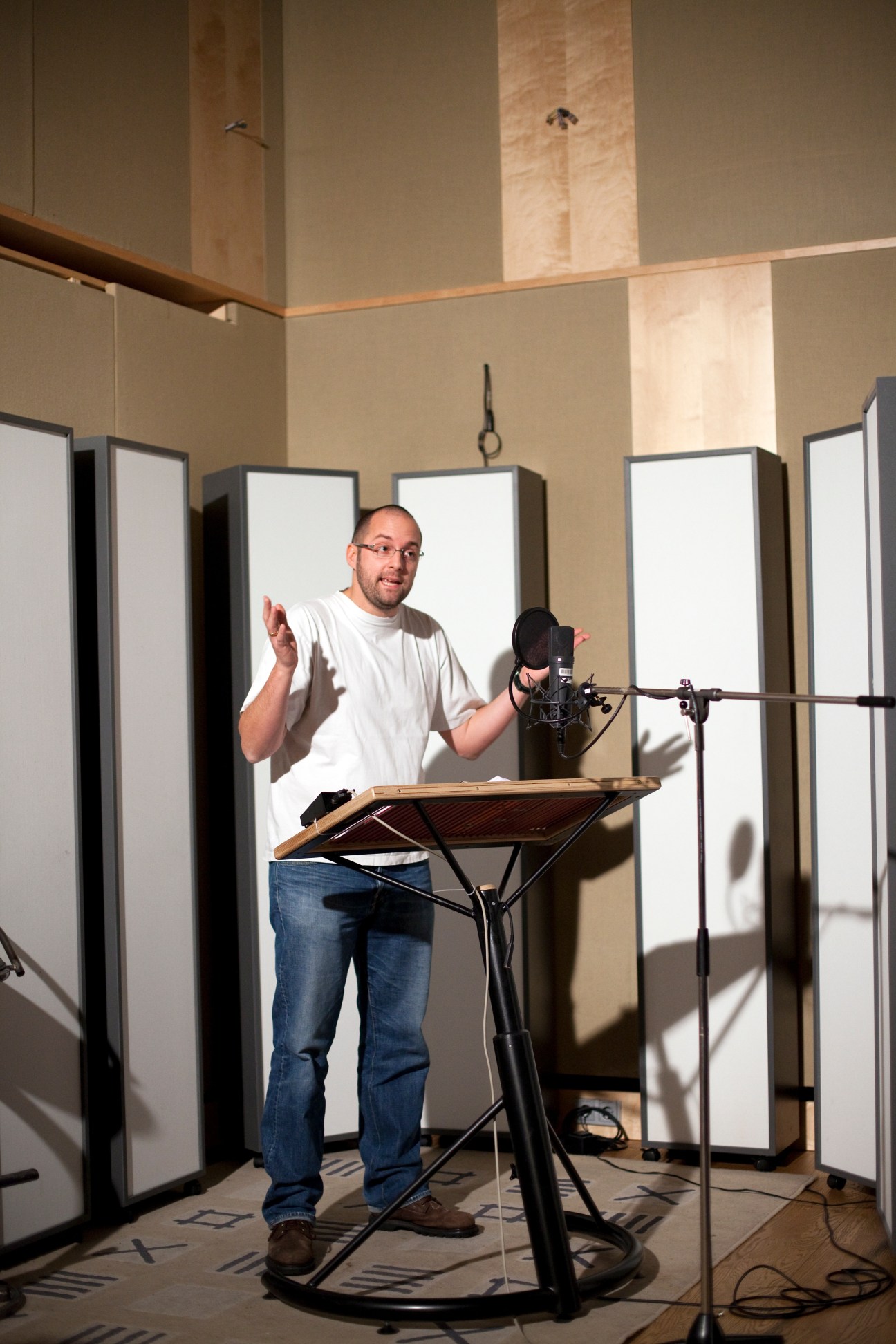 Marius Clarén, a German voice actor, performs at a microphone in a recording studio while reading from a script.