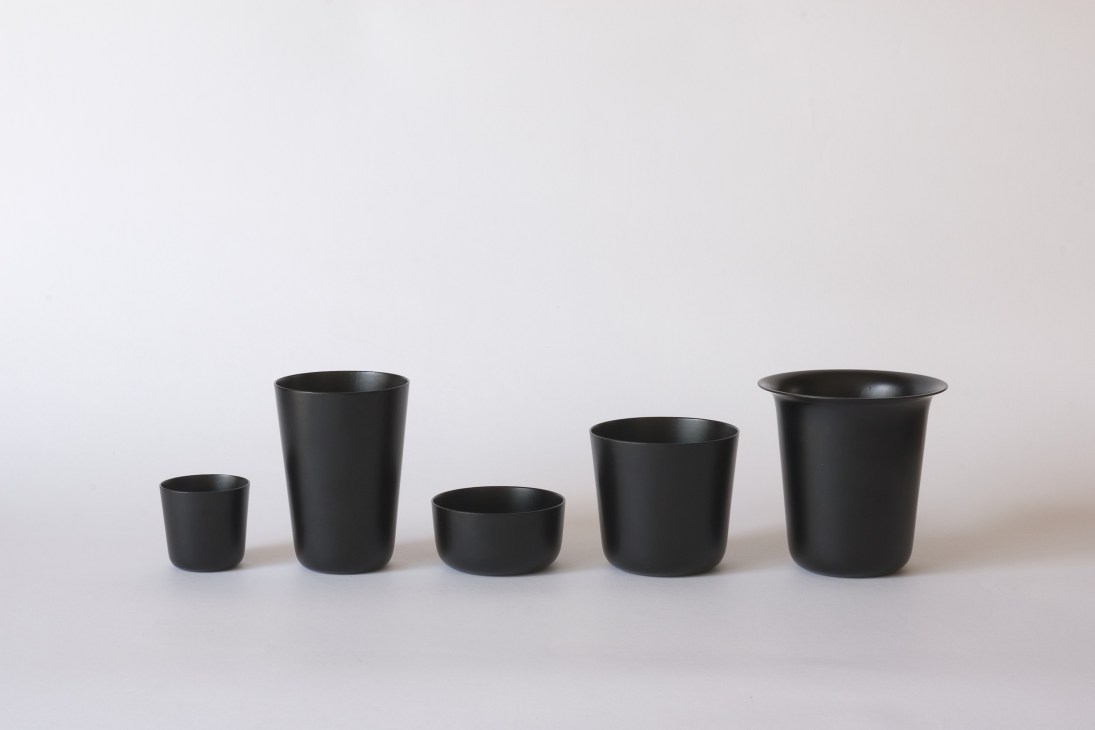 Five black cylindrical vessels of varying heights arranged in a row against a white background.