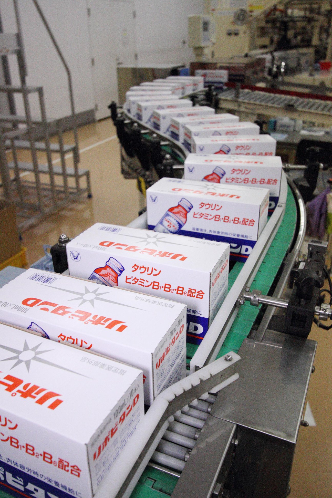 Boxed Lipovitan D nutrition drink cases moving along a conveyor belt in a manufacturing facility.