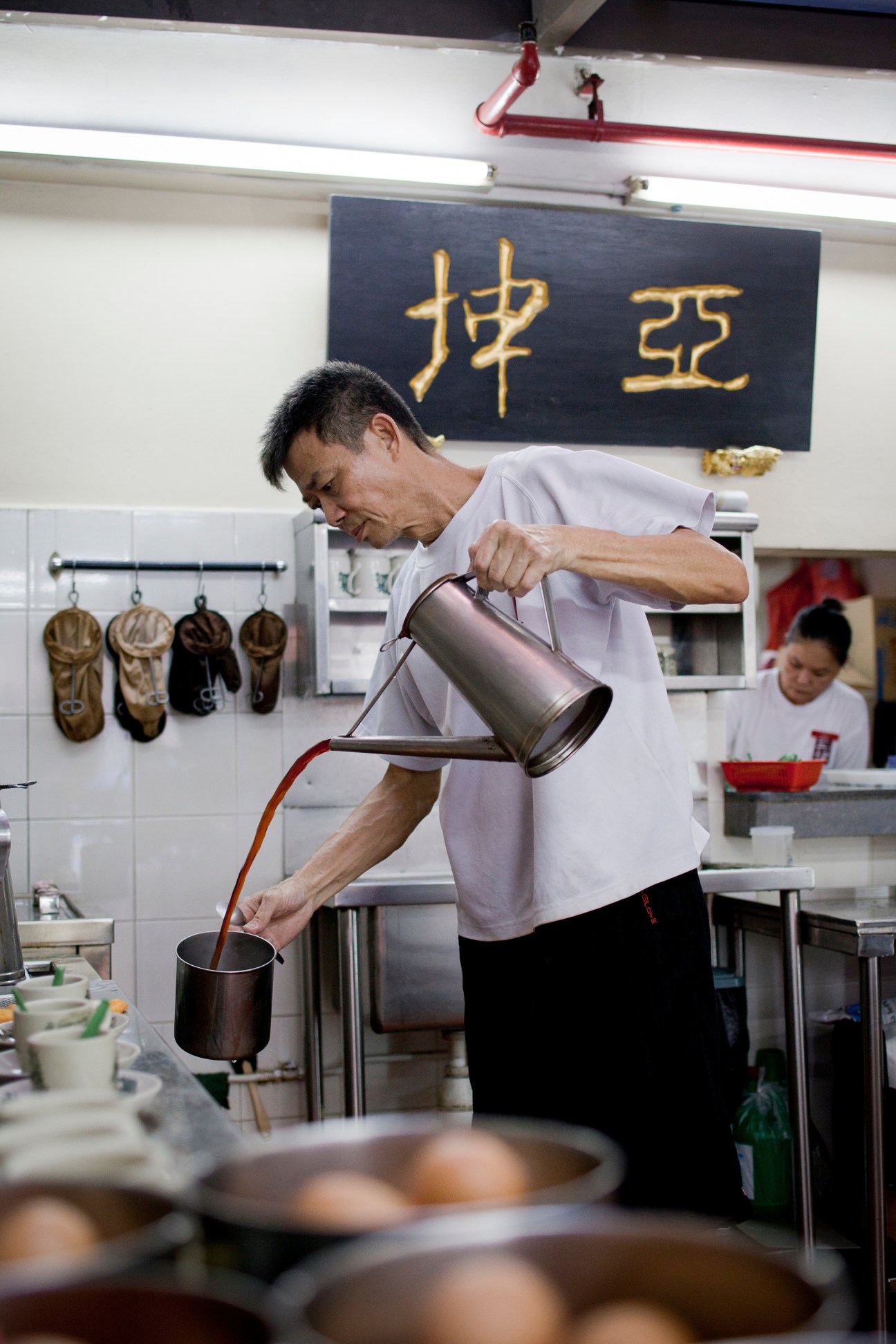 A barista pours coffee from a metal pitcher into a cup at Ya Kun kopitiam in Singapore.