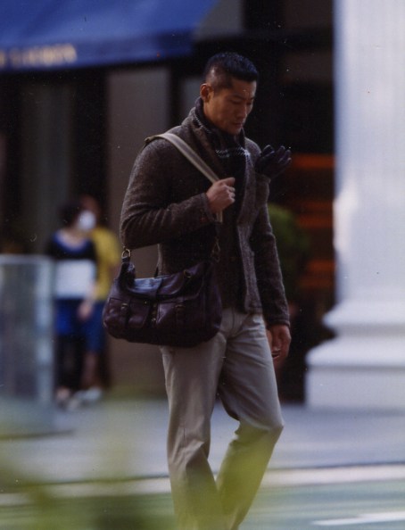 Man wearing Kolor cardigan and jacket with Post Overalls trousers and J&M Davidson bag on Tokyo street.