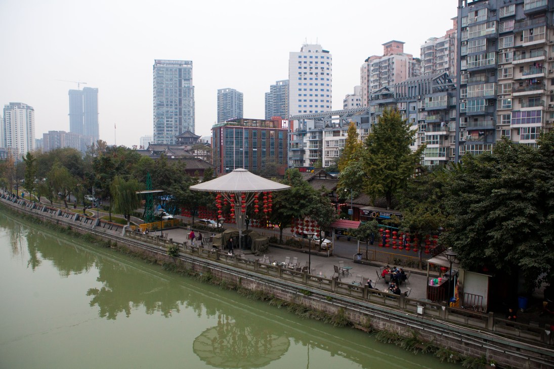View of Chengdu's Jin river with modern high-rise buildings and traditional structures along the waterfront.