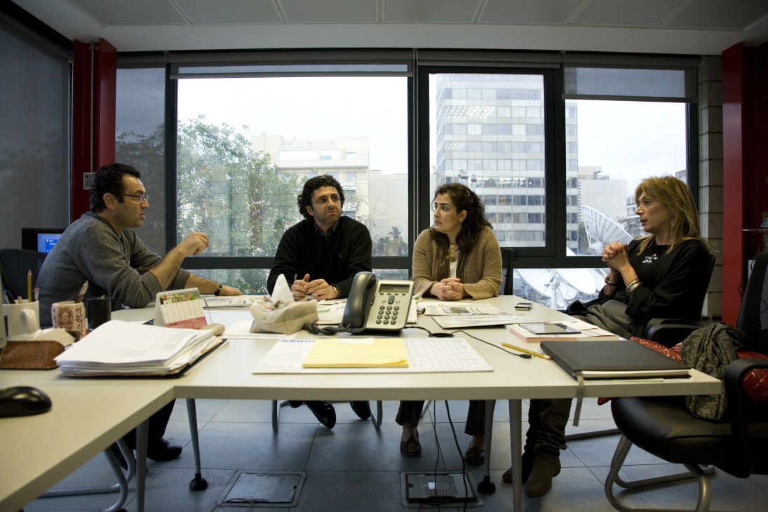 Four people in discussion at a conference table during an editorial meeting at Future News offices in Beirut.