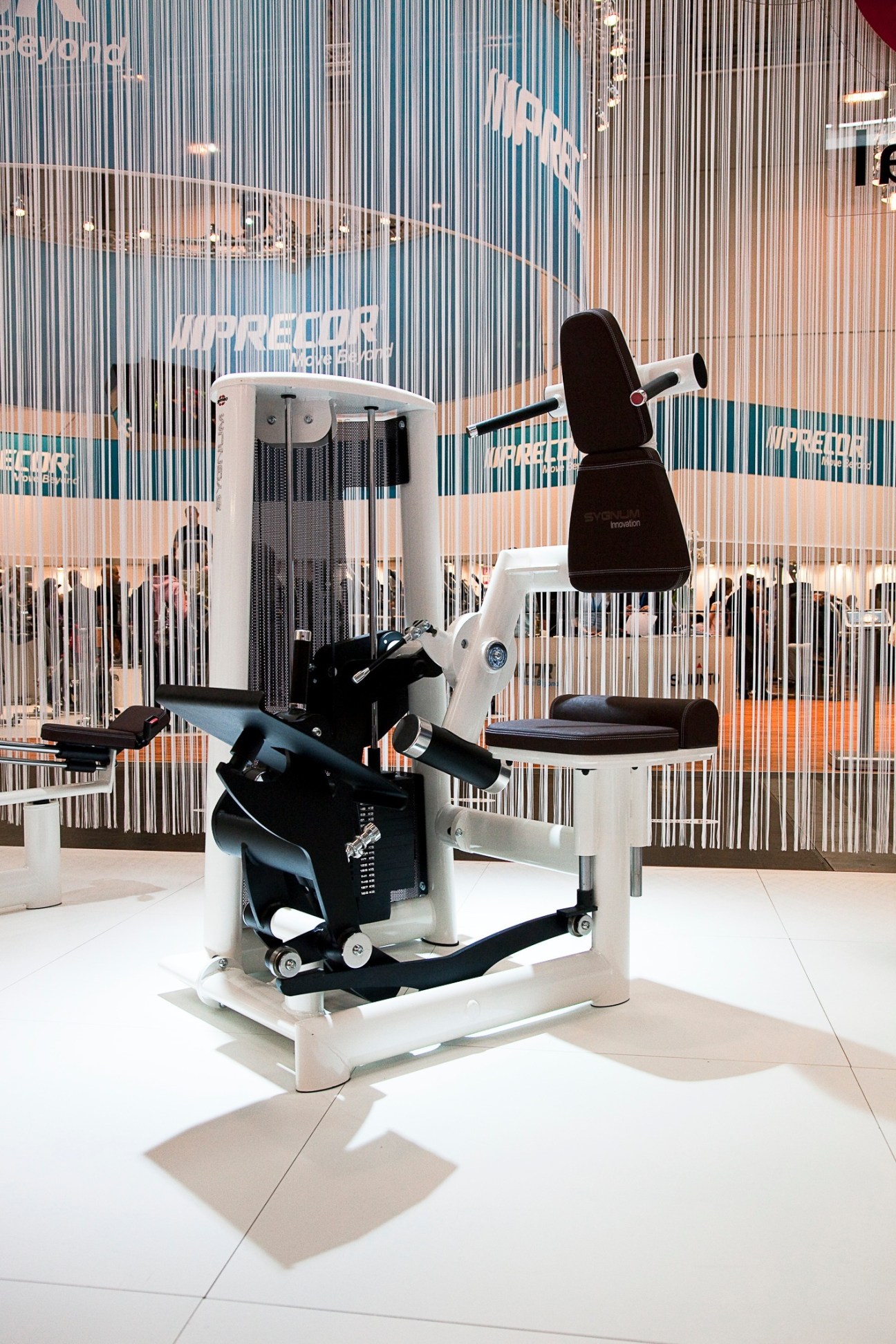 White and black leg press exercise machine with adjustable seat at Fibo trade show.