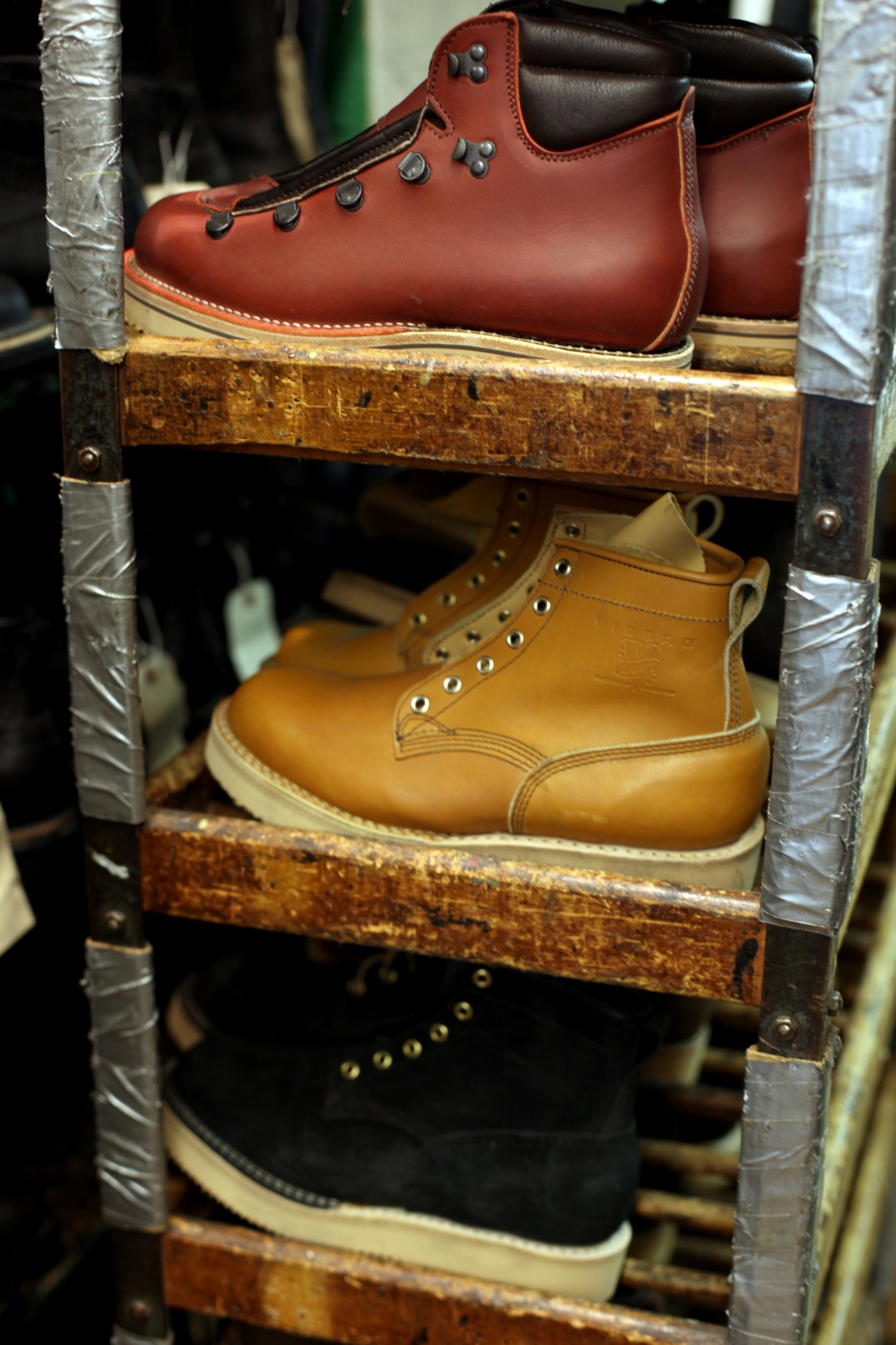 Viberg leather boots in red, tan, and black displayed on wooden shelves.
