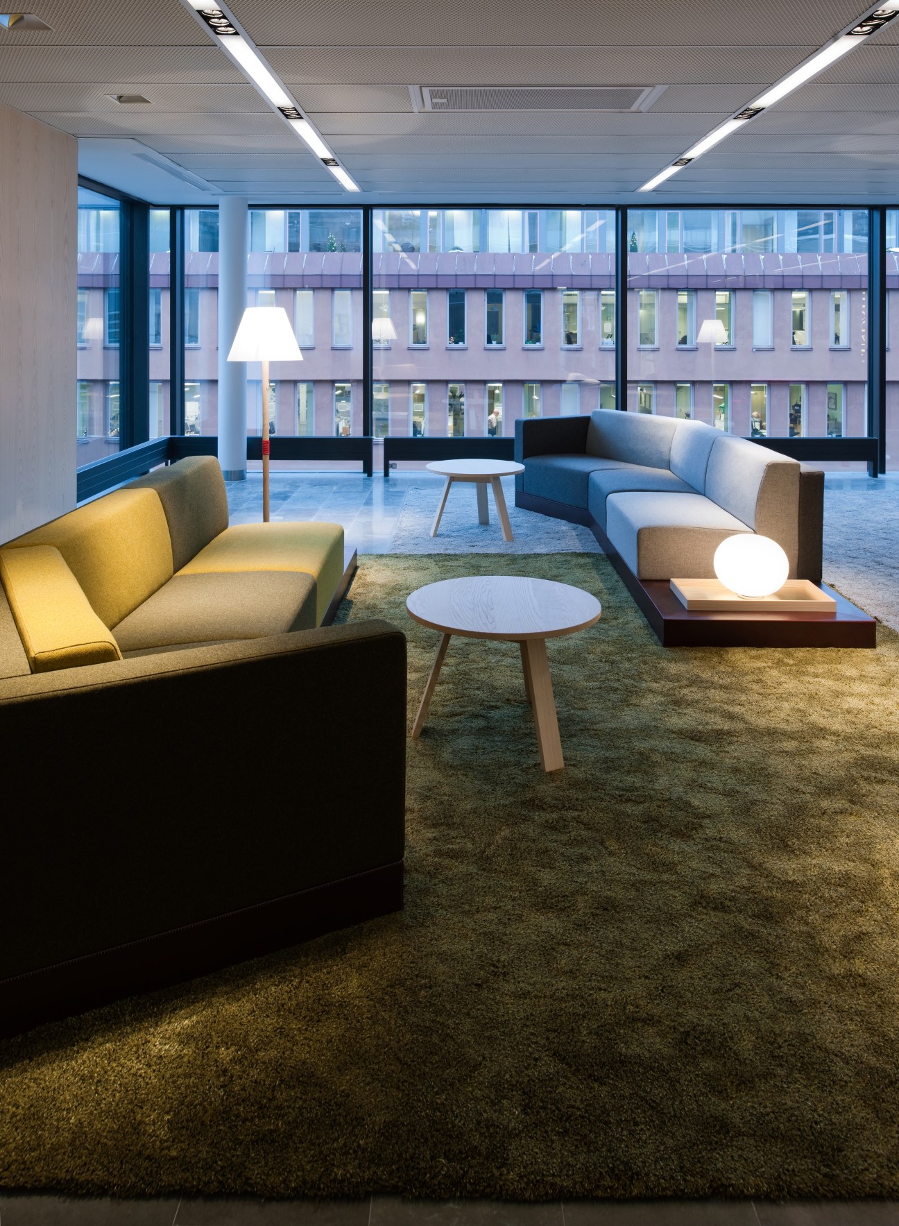 Modern lobby with colorful sofas, integrated lamps, and floor-to-ceiling windows overlooking Stockholm.