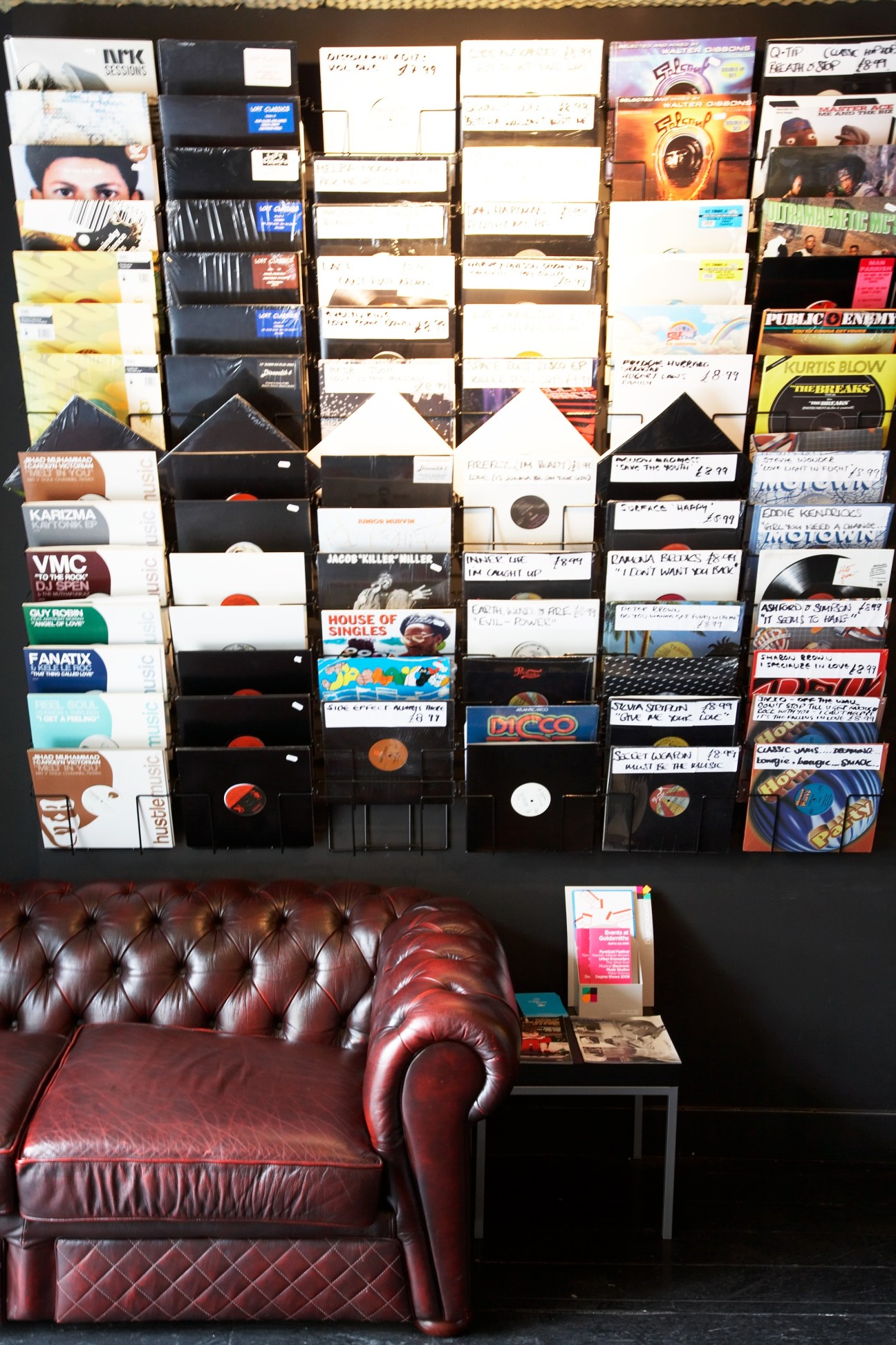 Record shop Symphonic displaying vinyl records organized on wall shelves with a burgundy leather Chesterfield sofa below.