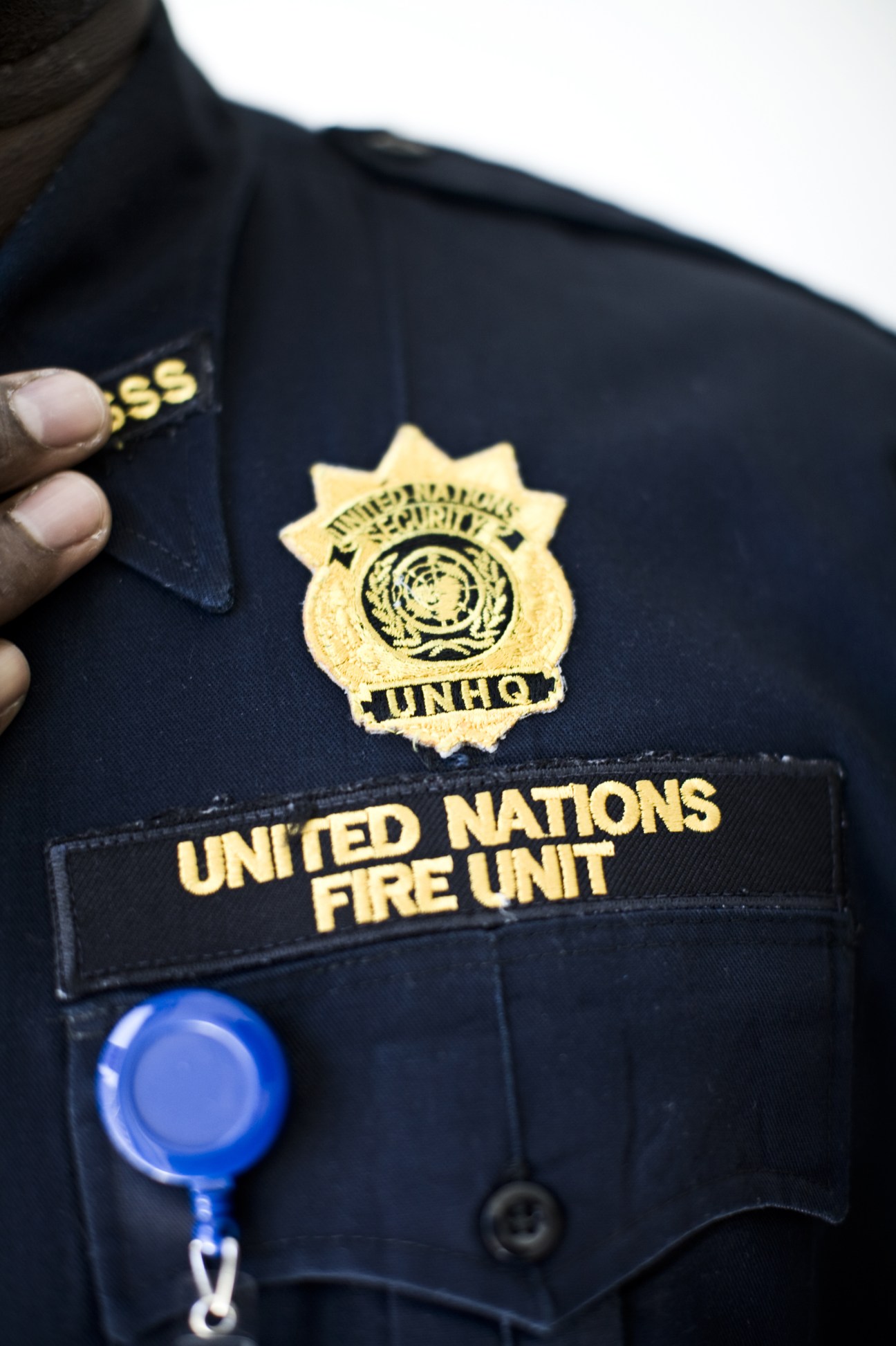 Close-up of a UN Fire Unit officer's uniform badge and nameplate on dark blue fabric.