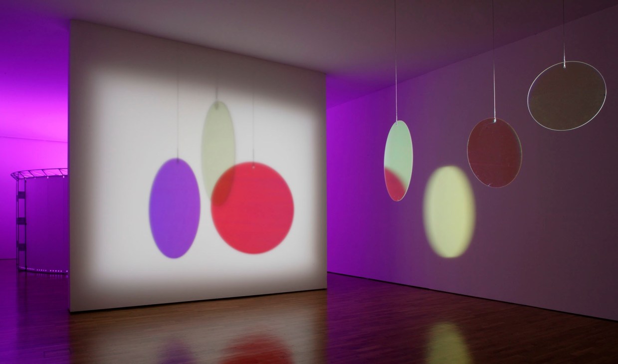 Installation view of Olafur Eliasson's Barcelona exhibition featuring illuminated colored spheres and ovals.