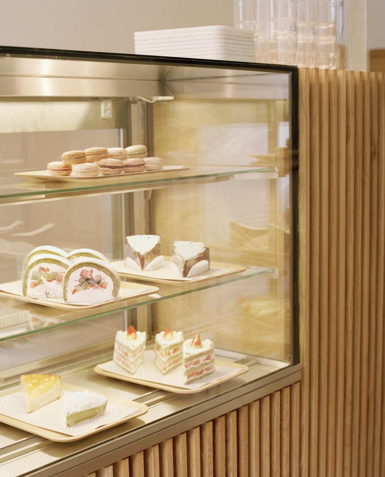 Display case with illuminated glass shelves showcasing assorted pastries and cakes from Lanka bakery.