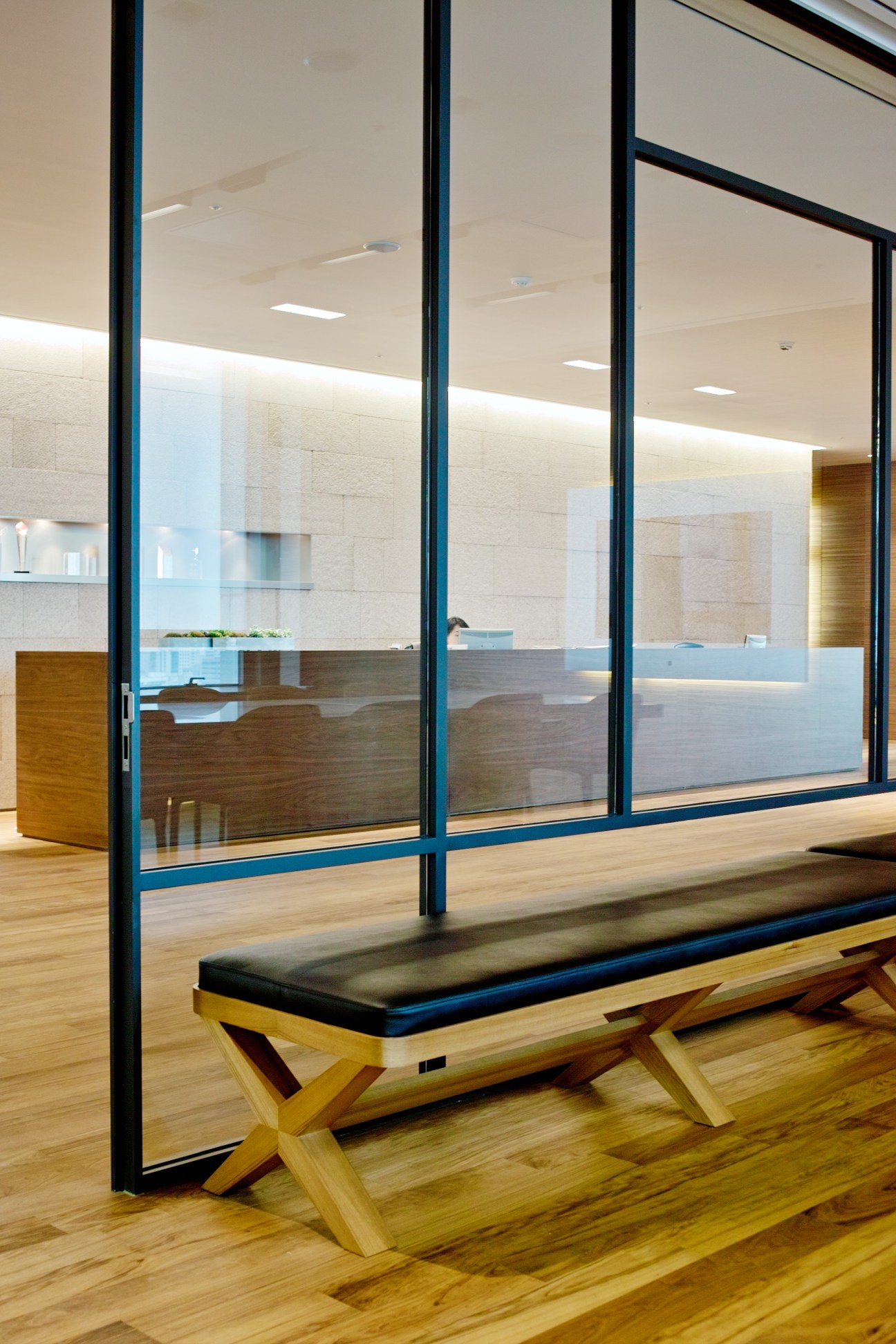 Glass partitions with black frames separate office spaces while maintaining visual openness and transparency.