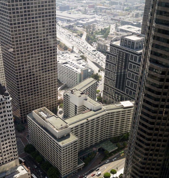 Aerial view of the Wilshire Grand Hotel surrounded by downtown Los Angeles high-rise buildings and freeway.