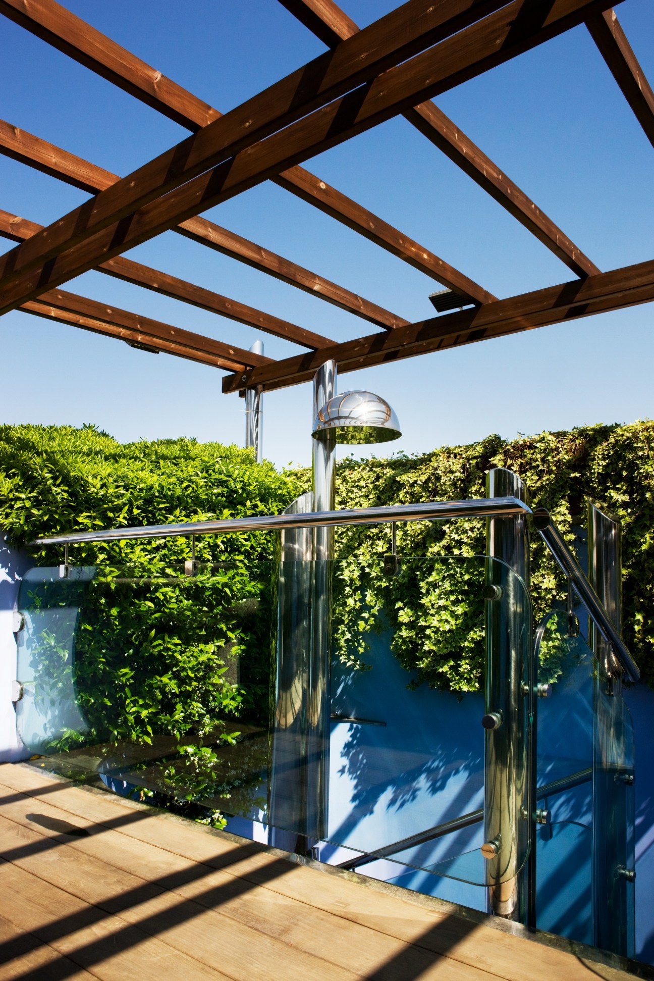 Teak observation deck with wooden pergola, metal railings, and heat lamp overlooking city views.