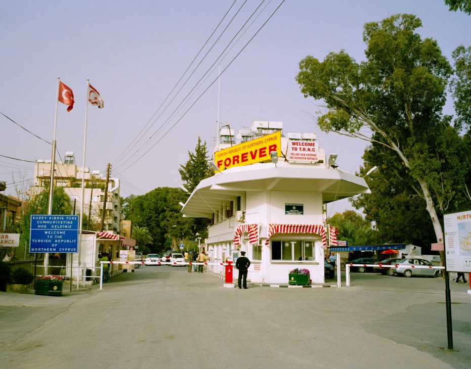 Border crossing checkpoint between Northern and Southern Cyprus with flags and welcome signage.