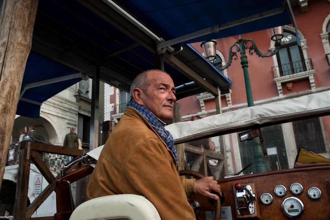 Gondolier operating a water taxi boat in Venice with historic buildings in background