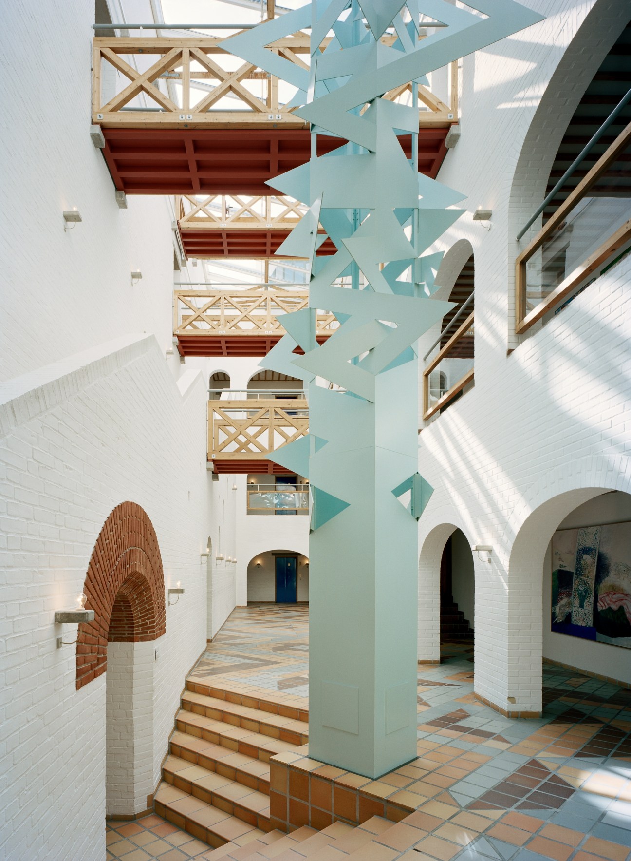 The Panoptikon hall interior with turquoise geometric sculpture, white brick walls, and wooden ceiling details.