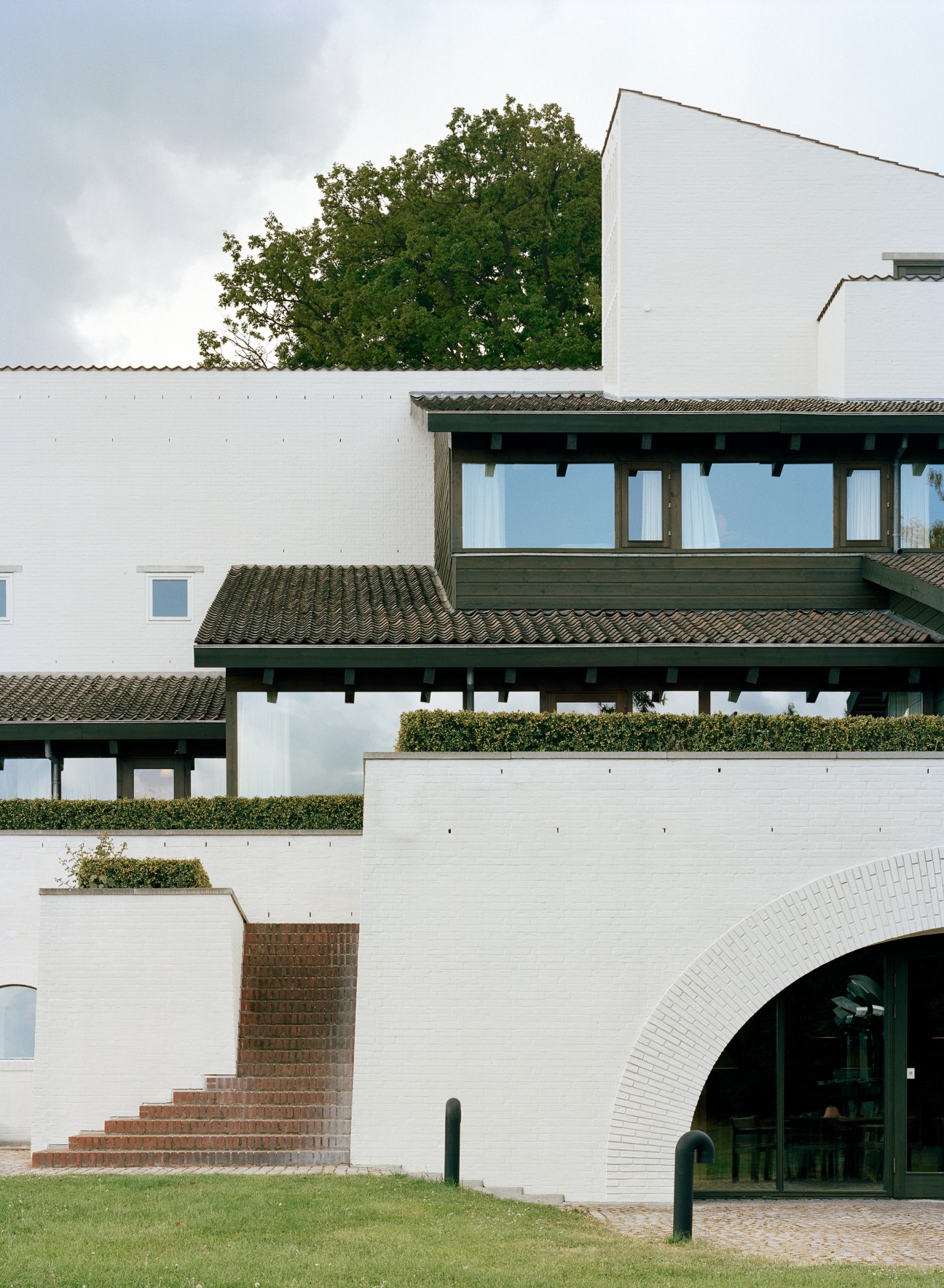 Lo-skolen's modernist white brick building with dark-tiled roofs and green-framed windows overlooking manicured gardens.