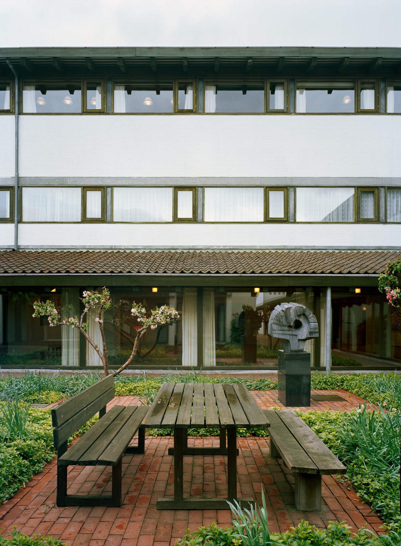 Lo-skolen residential building with white brick facade, green-framed windows, and courtyard seating area.