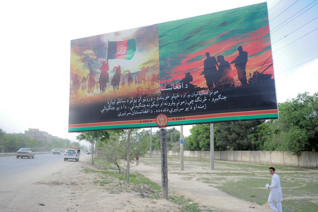 Afghan National Army recruitment billboard on Kabul street showing silhouetted soldiers and horsemen with flag.