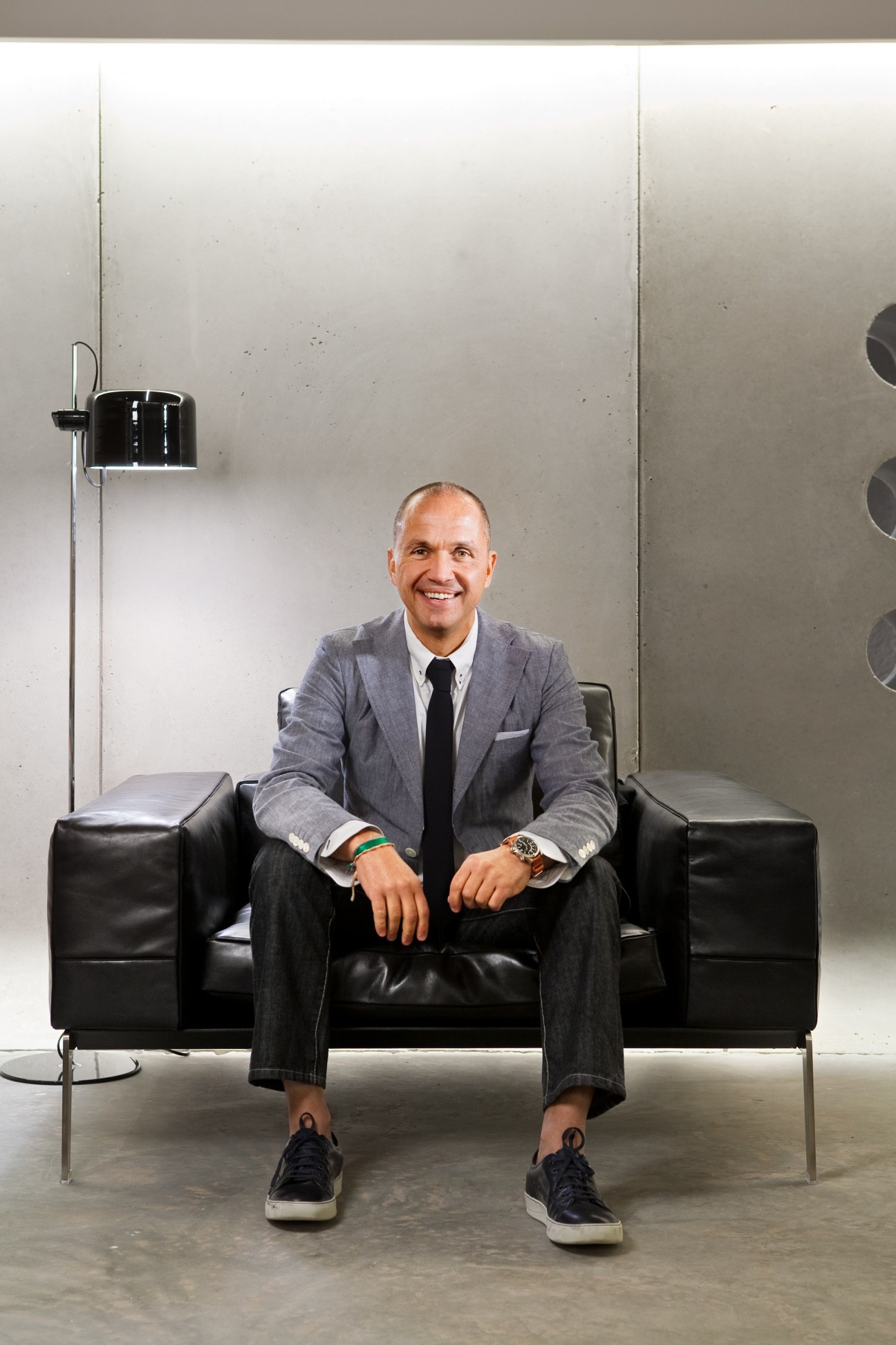 Grupo Habita founder Carlos Couturier sits on a black leather sofa in a minimalist interior.